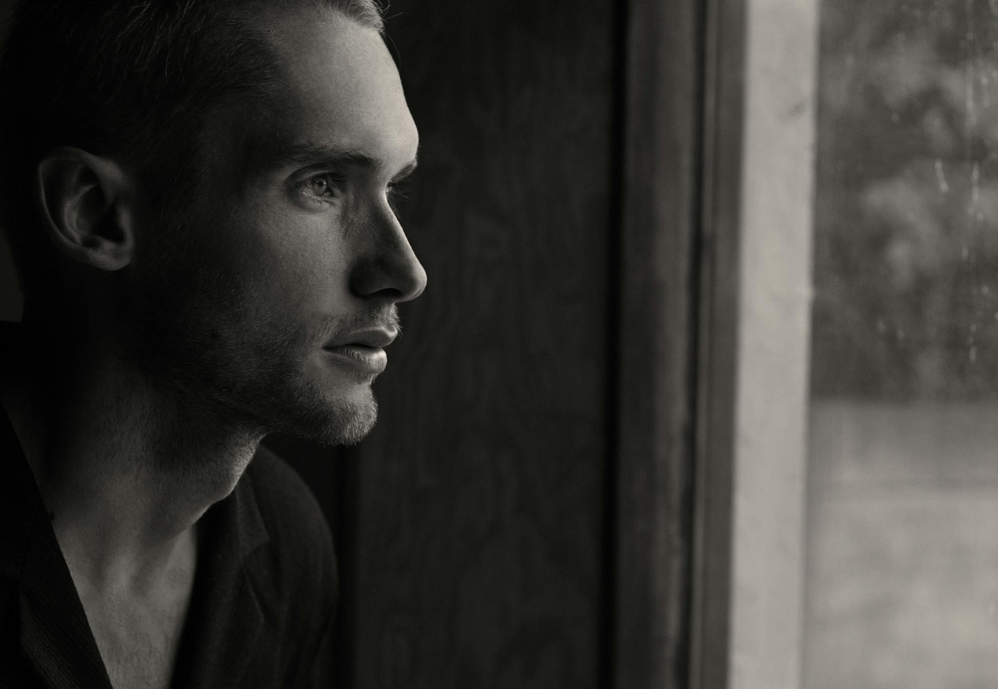 Grayscale Photography of Man Facing Glass Panel